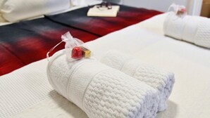 Una cama bien hecha con sábanas blancas y una pequeña bolsa de regalo sobre la almohada.