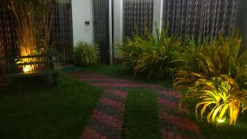 A pathway with red and black paving leading to a building with a glass door.