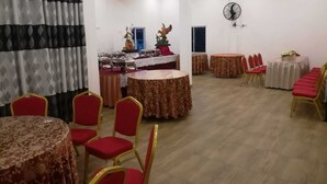 A banquet hall with round tables, red chairs, and a ceiling fan. - Randima Hotels (Negombo)