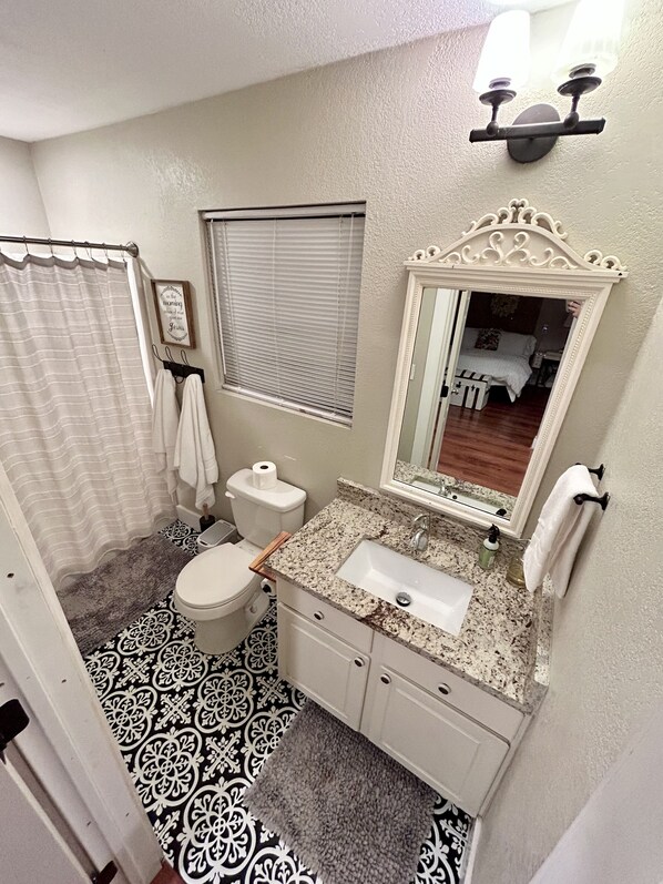 A bathroom with a toilet, sink, and mirror.