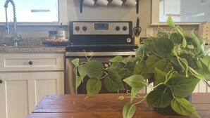 A kitchen with a wooden table, a stove, a sink, and a shelf with mugs and a sign. - House in Forney (Forney)