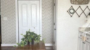 A dining area with a wooden table and chairs, a patterned rug, and a door with a decorative wall. - House in Forney (Forney)
