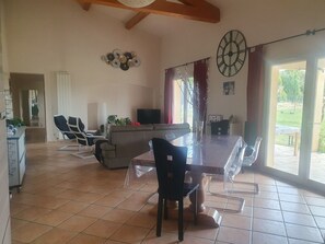 Amplia sala de estar con mesa de comedor, sillas, sofá y televisor.