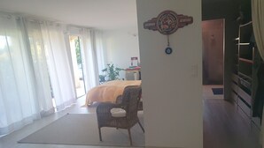 Ett hotellrum med en säng, en flätad stol, en skylt som hänger på väggen och en utsikt genom en dörr.