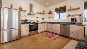 Una cocina moderna con electrodomésticos de acero inoxidable, estantes de madera y un ventanal grande.