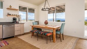 Una cocina moderna con comedor, ventanas amplias y vistas al paisaje.