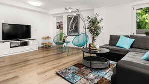 A modern living room with a flat-screen TV, teal chairs, a grey sofa, and a round coffee table. - Mola Apartments-Wetter/ 5 P/Parking/Terrasse/Grill (Wetter (Ruhr))