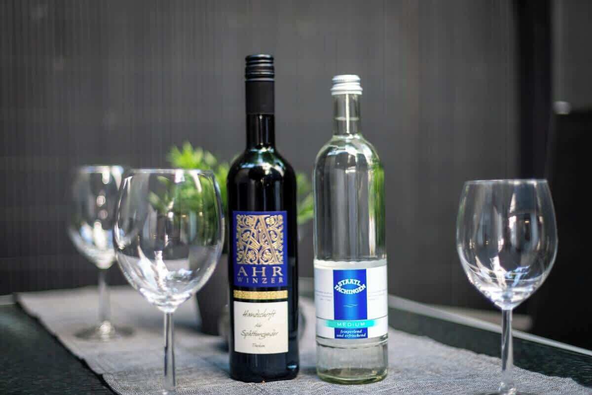 Two wine bottles and three wine glasses on a table.