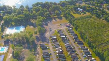 An aerial view of a residential area with a large body of water, a swimming pool, and a row of houses.