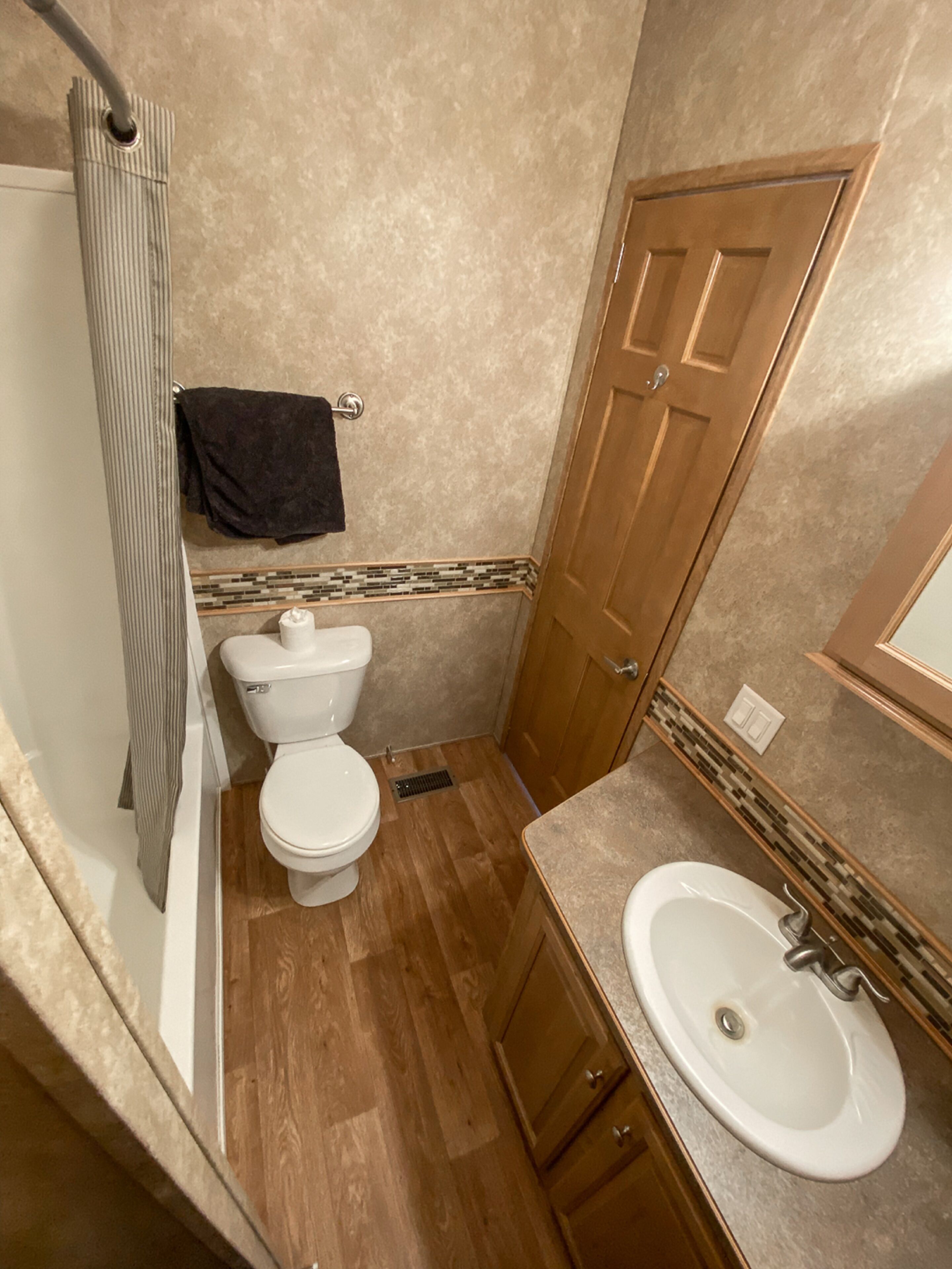 Un baño con inodoro, ducha, lavamanos y armarios de madera.