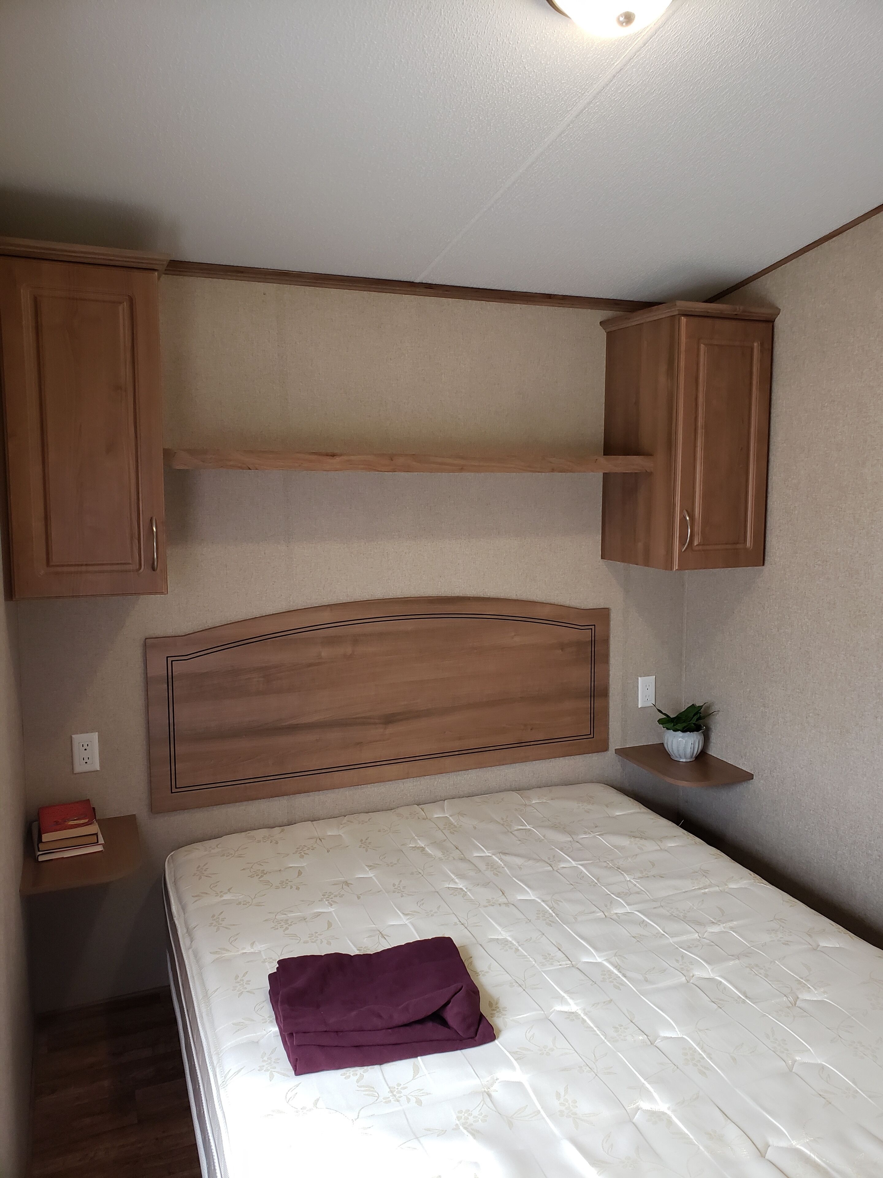 A bedroom with a bed, wooden headboard, and built-in cabinets.