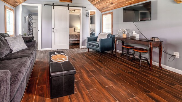 Una sala de estar moderna con techo de madera, un sofá, una mesa de centro, un televisor y un comedor con taburetes.