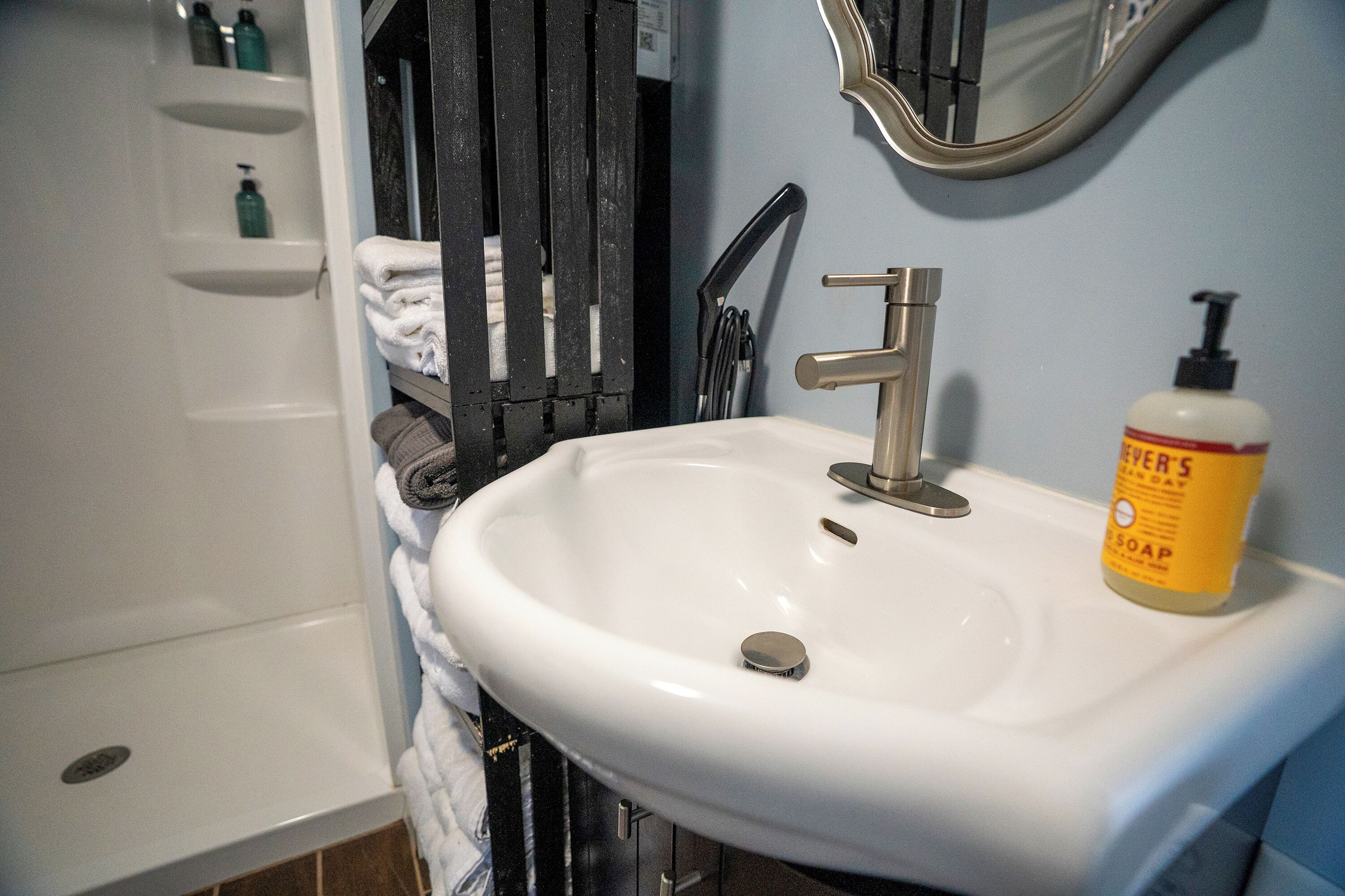 Un baño con lavamanos blanco, un espejo y una botella de jabón.