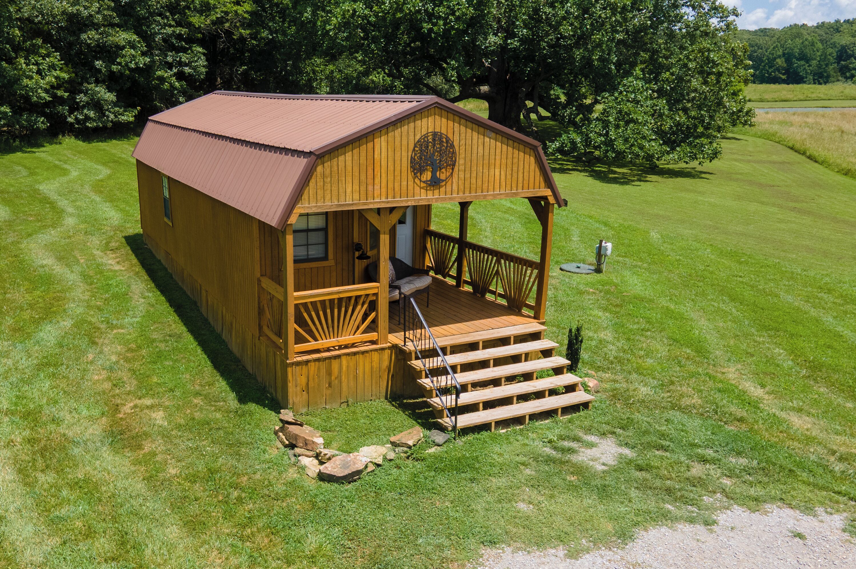 A wooden cabin with a porch, a small deck, and a stone pathway leading to the entrance.