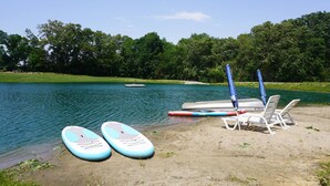 Eine Seelage mit Stand-Up-Paddles, einer Mole und Liegestühlen.