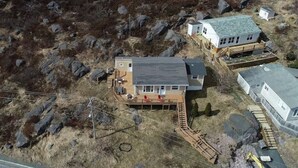 A house with a large deck, a garage, and a separate building with a sloped roof.