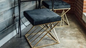 Un coin avec une table en métal et deux tabourets rembourrés, un mur en briques et une corde.