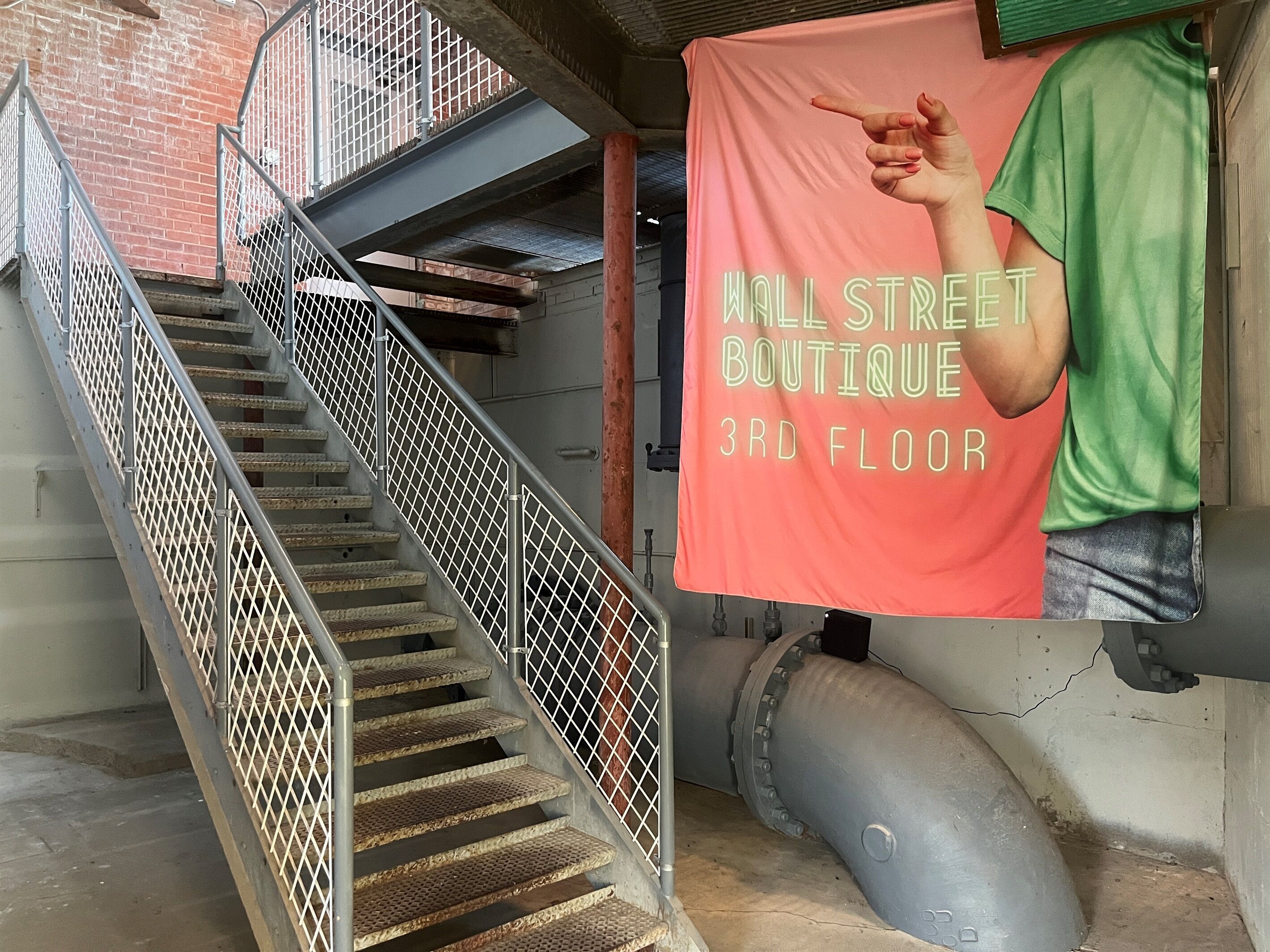 Een trap met metalen leuningen die naar een boetiek op de derde verdieping leidt.