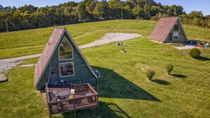 A triangular A-frame house with a deck and outdoor seating area. - 2BR A-Frame Cabin w/ Hot Tub Near Wine Trail (Makanda)