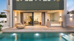 Una casa moderna de dos pisos con piscina, balcón e interior bien iluminado.