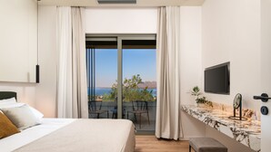 Habitación de hotel moderna con una cama grande, un balcón con vista al mar, una encimera de mármol y un televisor de pantalla plana.