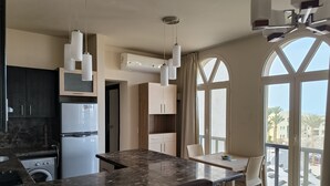 A modern kitchen with a marble countertop, built-in appliances, and pendant lighting.