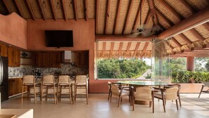 A modern kitchen with a TV, wooden cabinets, and a dining area with a glass table and chairs.