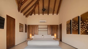 A spacious bedroom with a large bed, wooden ceiling beams, and two bedside lamps.