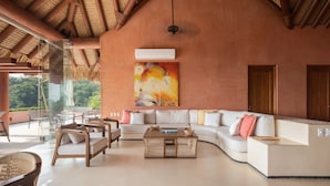 A spacious living area with a large sofa, a coffee table, and a painting on the wall.
