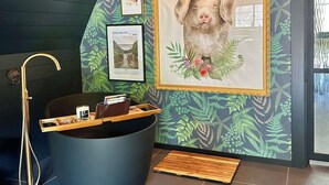Une salle de bain dotée d’une grande baignoire, d’une douche et d’un mur orné de tableaux encadrés.