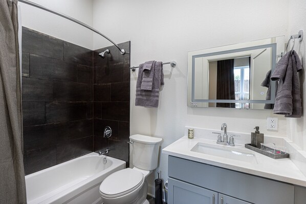 A modern bathroom with a bathtub, toilet, and vanity.