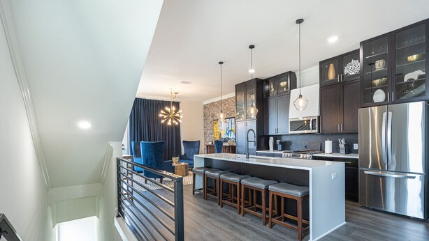 A modern kitchen with dark cabinets, stainless steel appliances, and a central island with bar stools.