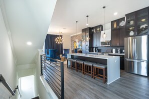 A modern kitchen with dark cabinets, stainless steel appliances, and a central island with bar stools.