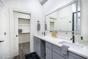 Un baño moderno con un espejo grande, dos lavamanos y un vestidor.