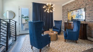 A modern living room with a brick wall, a large abstract painting, and a unique chandelier.