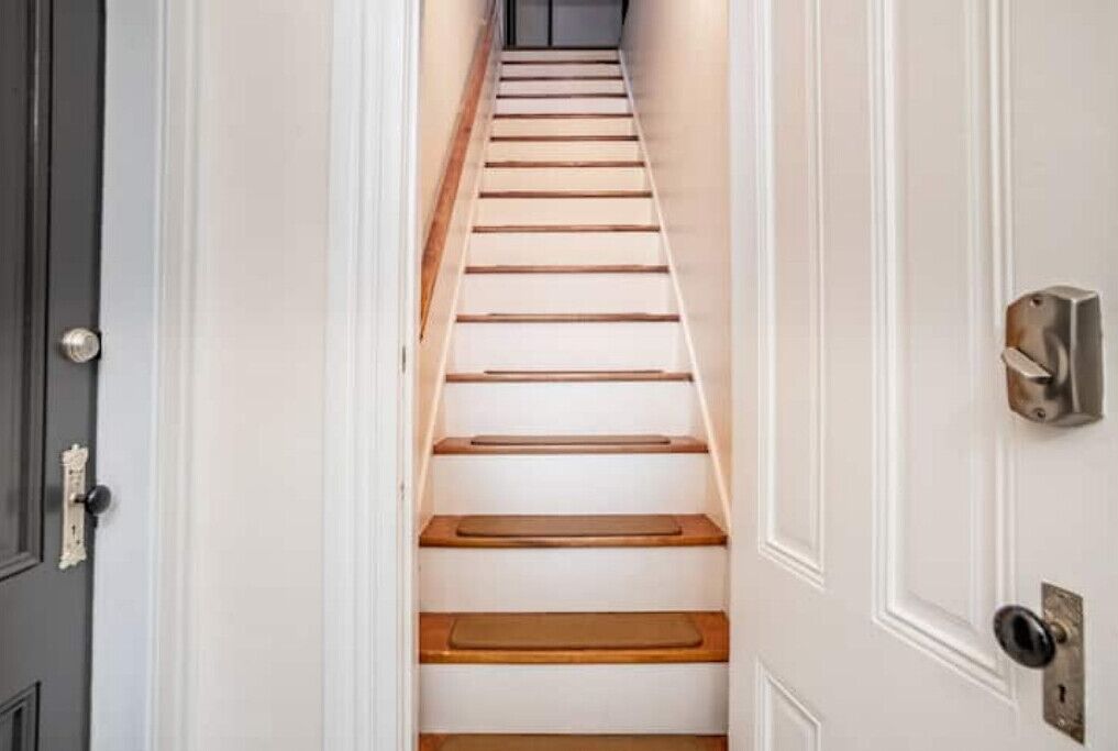 A narrow stairway with wooden steps leading to a landing.