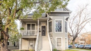 A two-story house with a front porch, a staircase leading to the entrance, and a garage. - Sac City Loft (Sacramento)