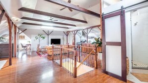 A spacious loft with high ceilings, exposed wooden beams, and a central staircase. - Sac City Loft (Sacramento)