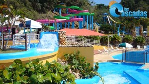 Un parque acuático con piscina, toboganes y una zona techada.