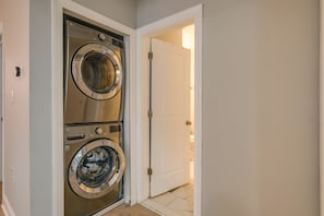 A laundry room with two stacked front-loading washing machines and a white door leading to another room.
