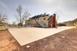 Een gebouw met twee verdiepingen, een overdekte patio, een trap en een geparkeerd voertuig op de achtergrond.