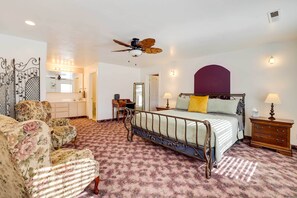 Een slaapkamer met een bed, een stoel, een bureau en een plafondventilator.