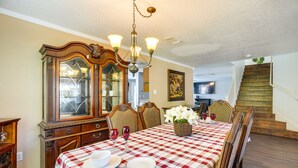 A dining room with a checkered tablecloth, wooden chairs, a chandelier, and a large mirror. - San Antonio Home w/ Private Hot Tub + Pool! (San Antonio)