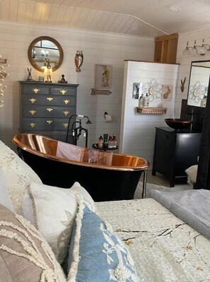 A bedroom with a bathtub, a dresser, and a mirror. - The Burrow Tiny Luxury (Clayton)