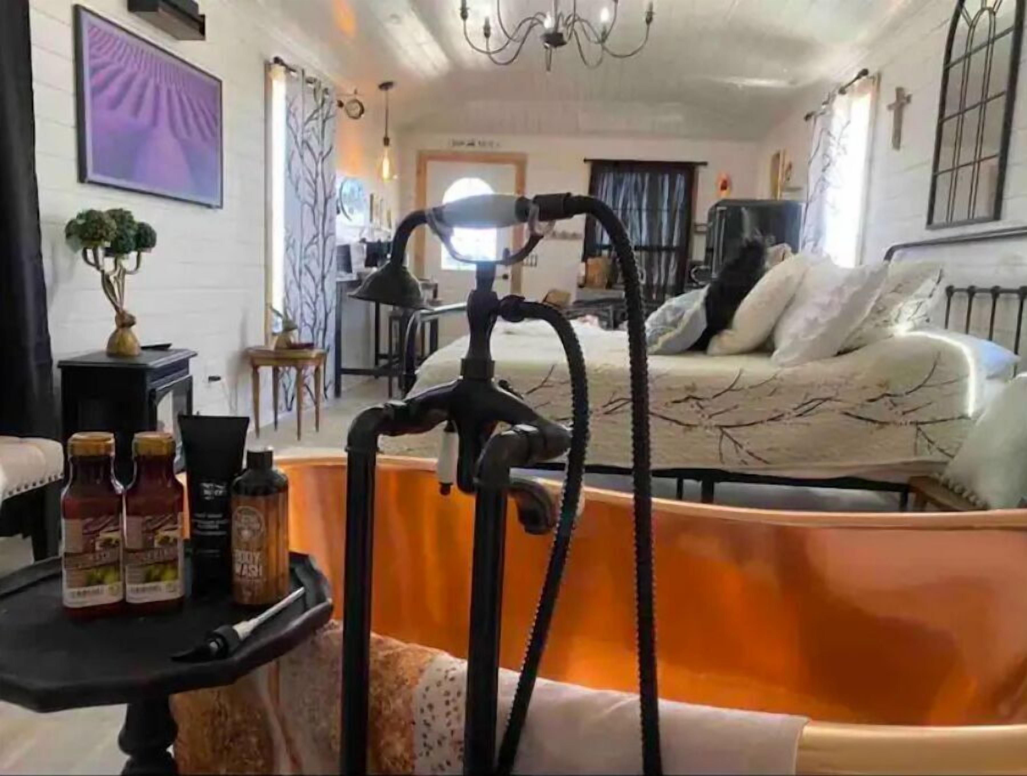 Une pièce comprenant un lit, un bureau avec une chaise, un lustre et une fenêtre avec des rideaux.