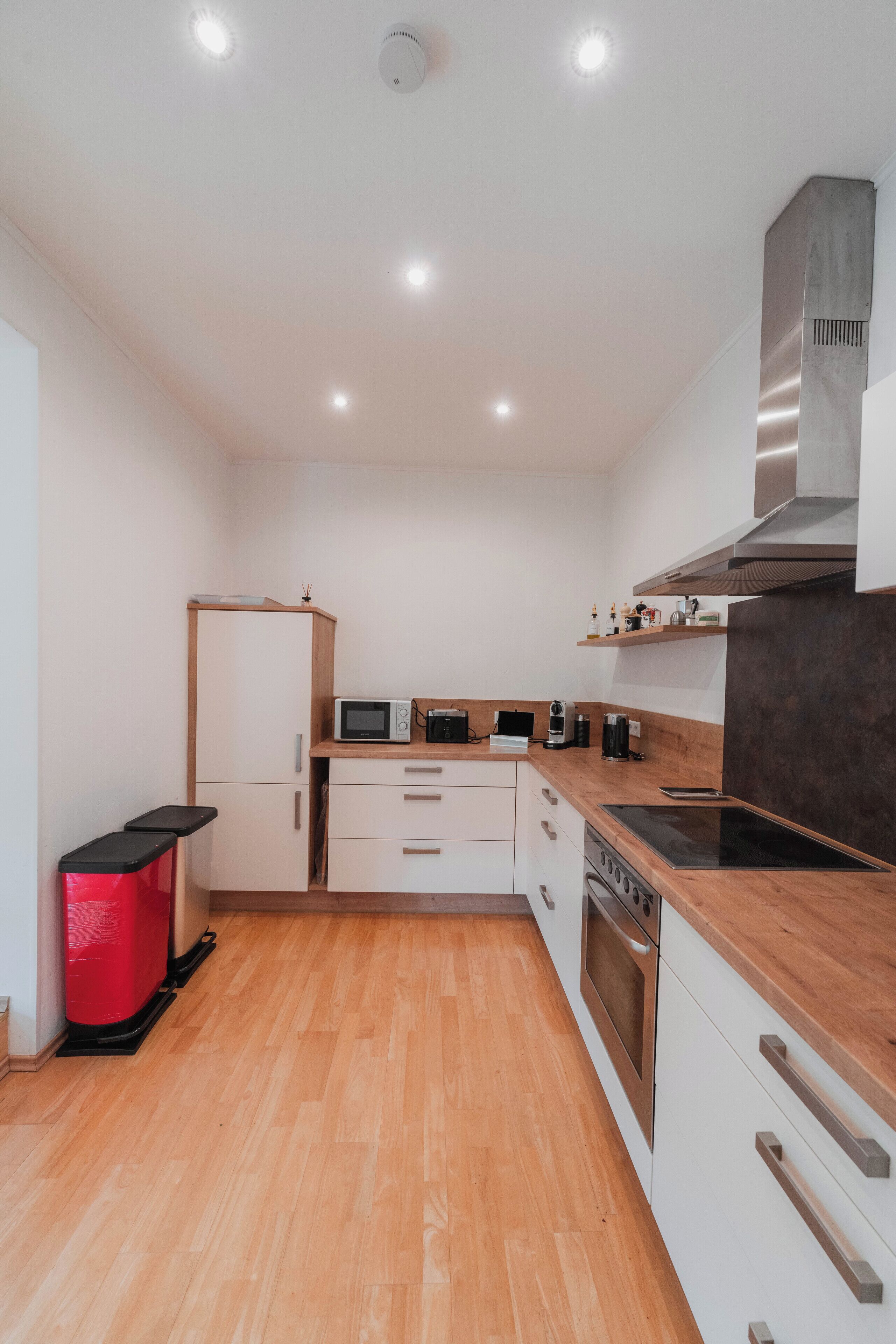 A compact kitchen with white cabinets, a microwave, a toaster, a coffee maker, and a stove.