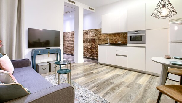 Un soggiorno moderno con un divano, una televisione e un'area pranzo con tavolo e sedie.