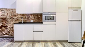 Una cucina moderna con mobili bianchi, una parete in mattoni e un pavimento in legno.