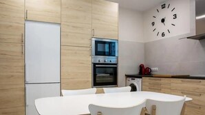 Eine moderne Küche mit Holzausstattung, einem eingebauten Backofen, einer Mikrowelle und einer Waschmaschine.