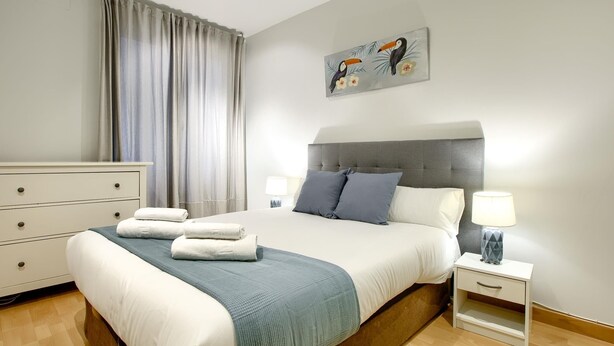 A bedroom with a bed, bedside tables, a dresser, and a painting on the wall. - Callao Central - Renovated and Central Apartment (Madrid)